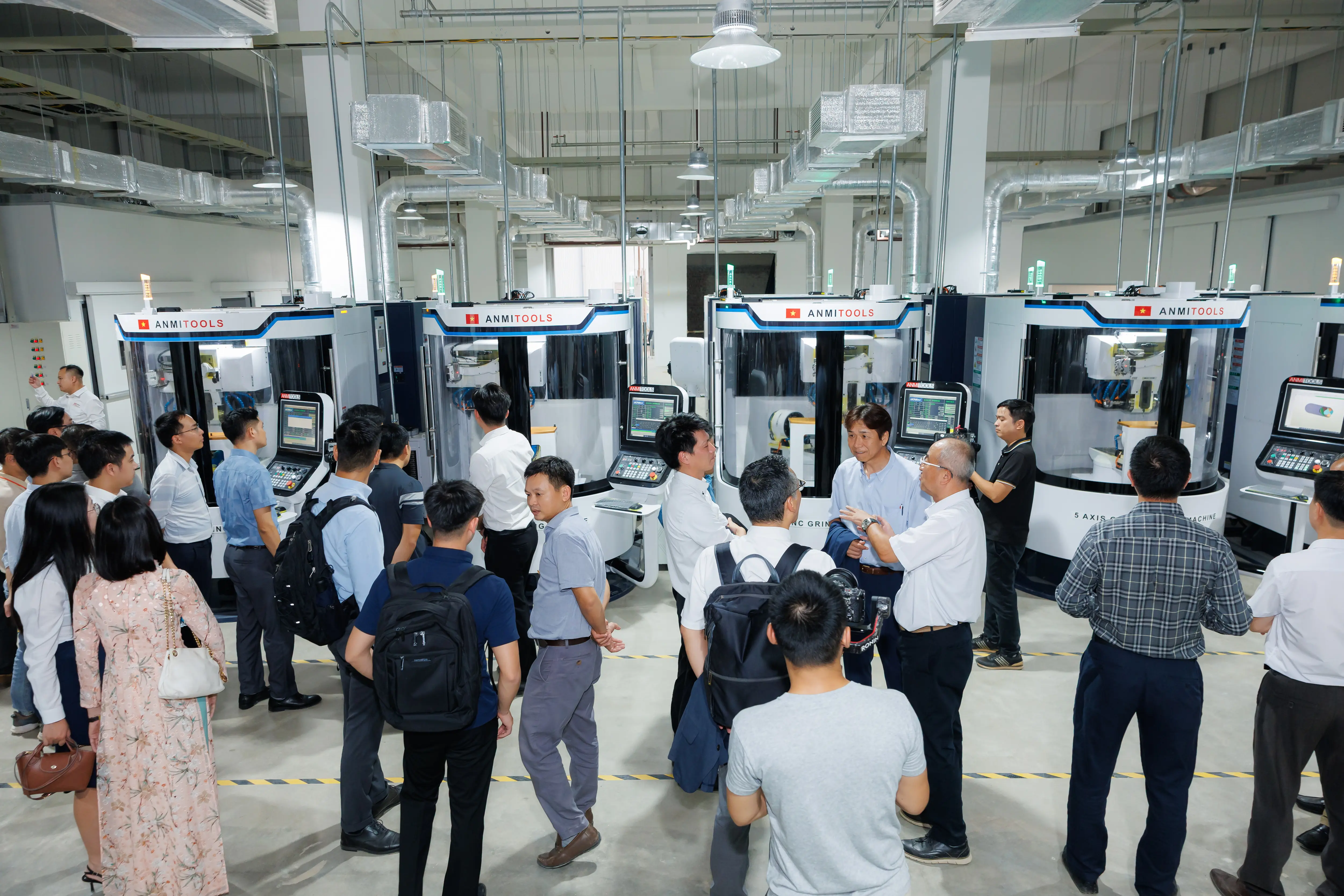 Đoàn khách nghe giới thiệu tại khu vực máy móc trong nhà máy